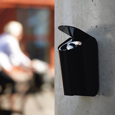 A small ashtray mounted to a wall on the side of a building.